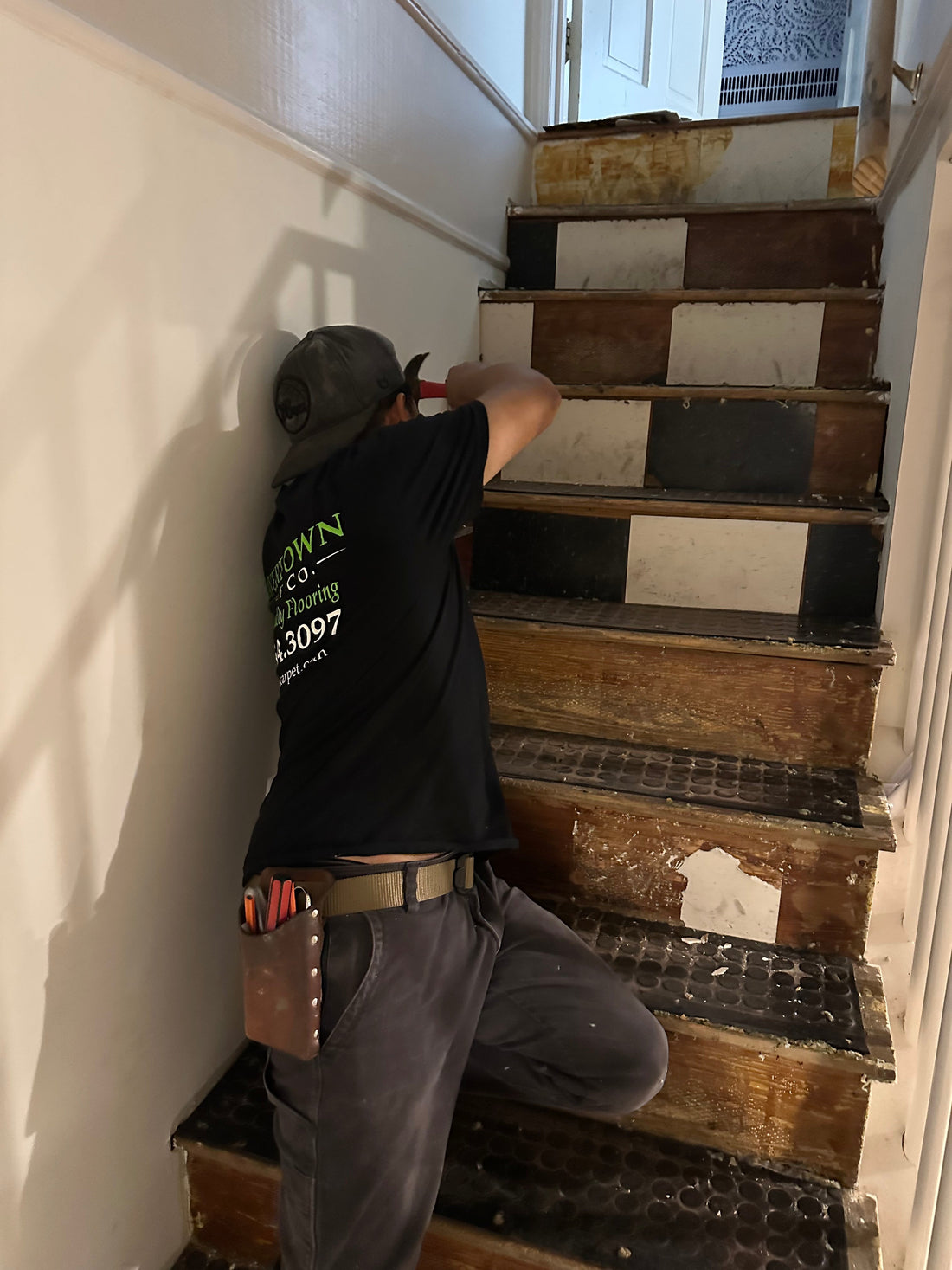 A carpet installer in uniform in Chester County installing new flooring on basement steps